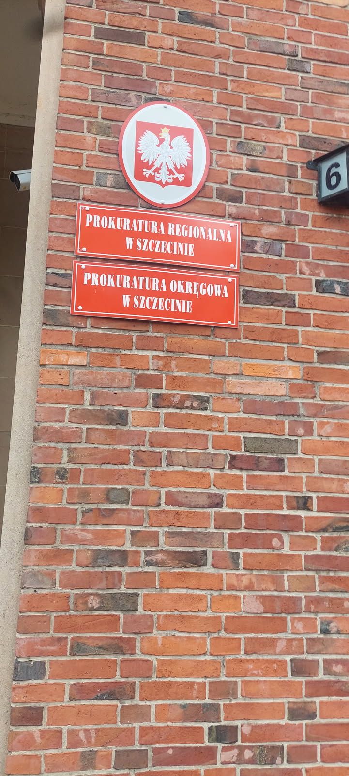 Tablice Prokuratur w Szczecinie na ceglanej ścianie.